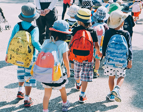 Mazi bērni ar mugursomām dodas uz skolu